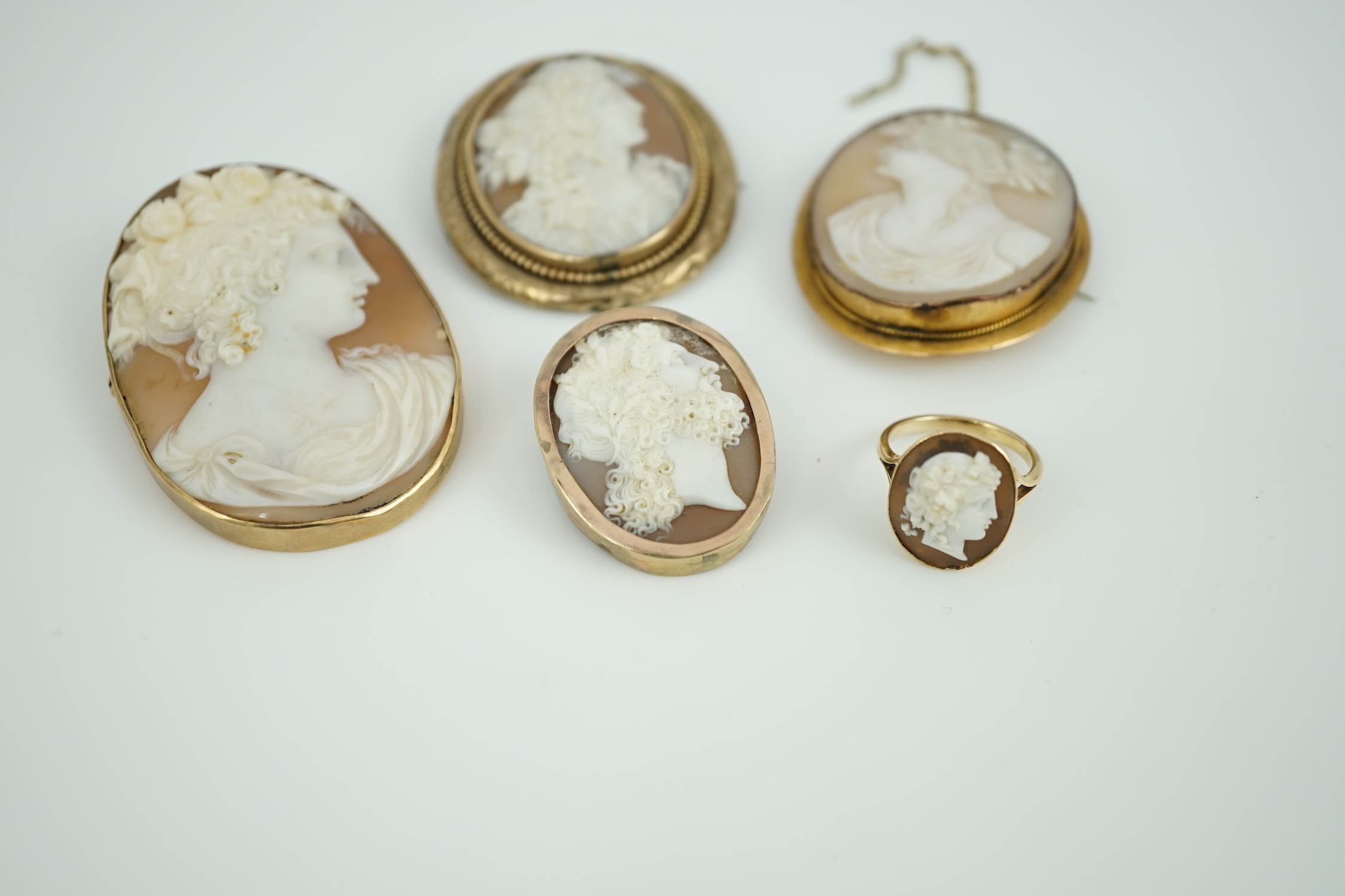 Four assorted early 20th century yellow metal mounted oval cameo shell brooches, largest 60mm, one stamped 9ct and a yellow metal mounted oval cameo shell ring.